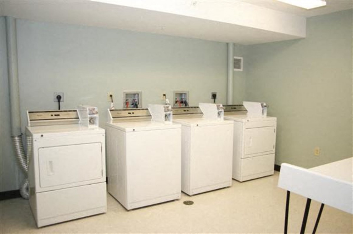A clean and organized laundry room with multiple washing machines and dryers.