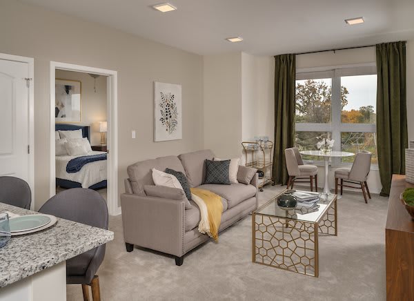 A modern apartment living room with a comfortable sofa, stylish artwork, and a view into the bedroom area.