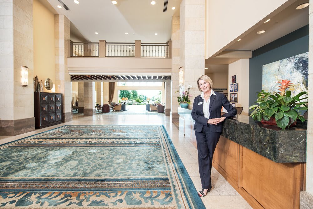 A person in business attire standing in a spacious hotel lobby with elegant decor.