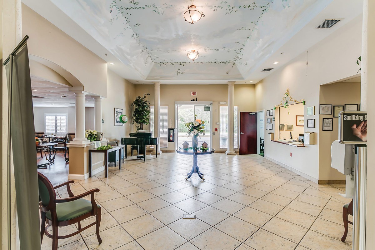 Spacious lobby with tile flooring and decorative ceiling, featuring elegant furniture and greenery.