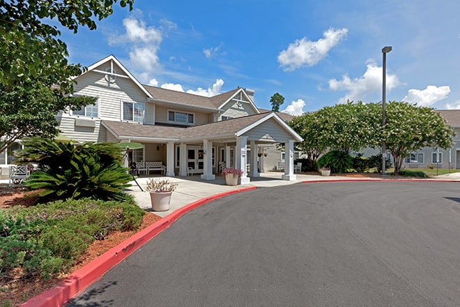 A suburban building with a driveway and landscaped surroundings under a blue sky.