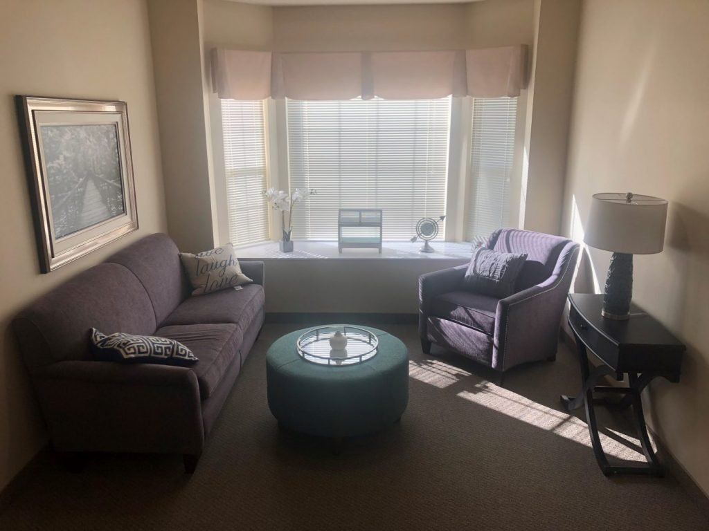 A cozy living room with a sofa, armchair, and a coffee table by the window.