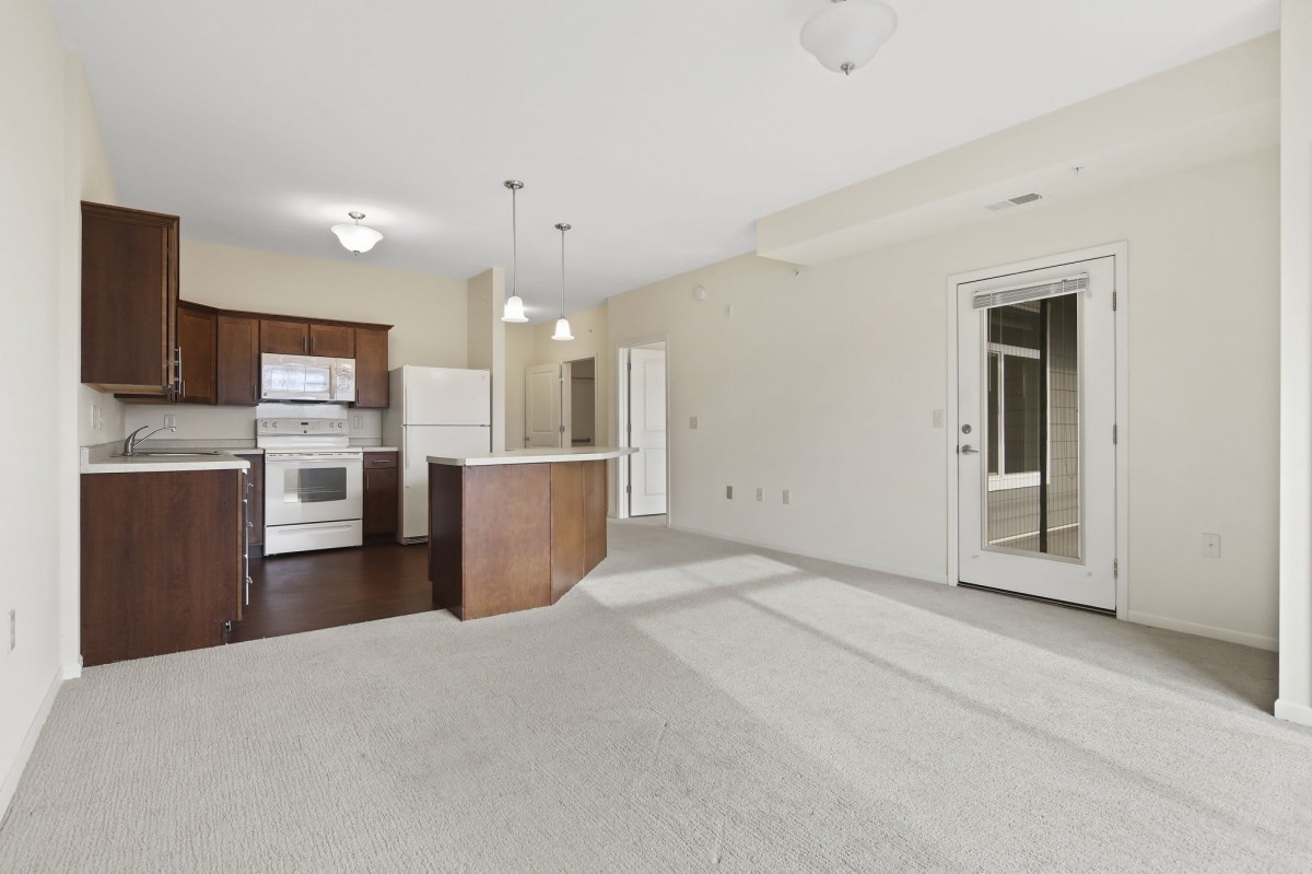 A modern, empty apartment interior showcasing an open floor plan with a kitchen and living area.