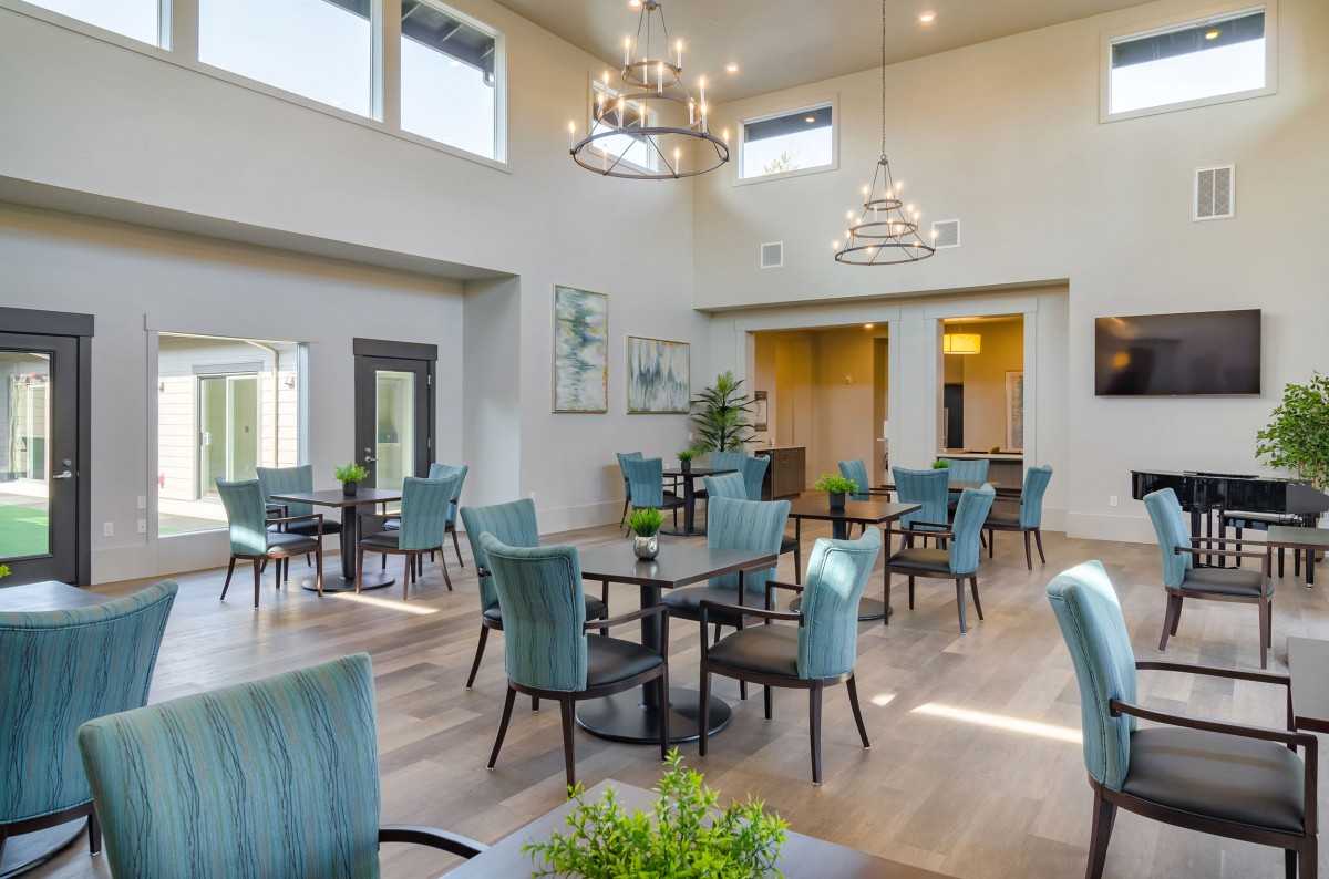 A spacious, well-lit dining area with modern decor and elegant chandeliers.
