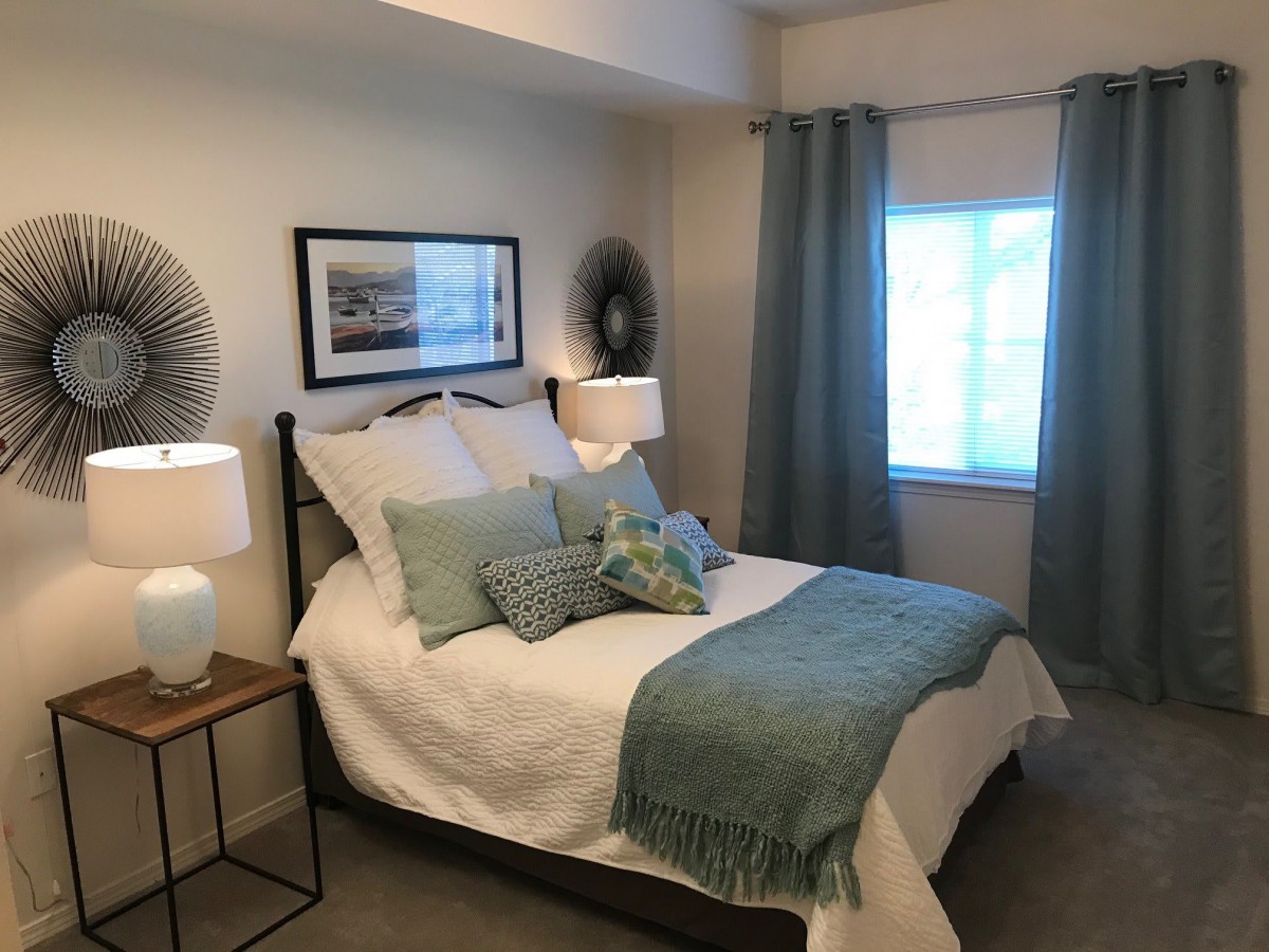 A cozy bedroom with a neatly made bed, decorative pillows, and soft lighting.