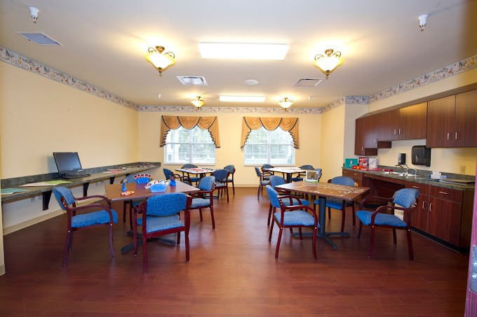A well-lit dining area with multiple tables and chairs, featuring wooden floors and decorated windows.