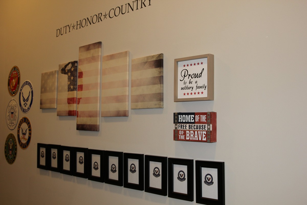 A wall decorated with patriotic and military-themed artwork alongside framed family photos.