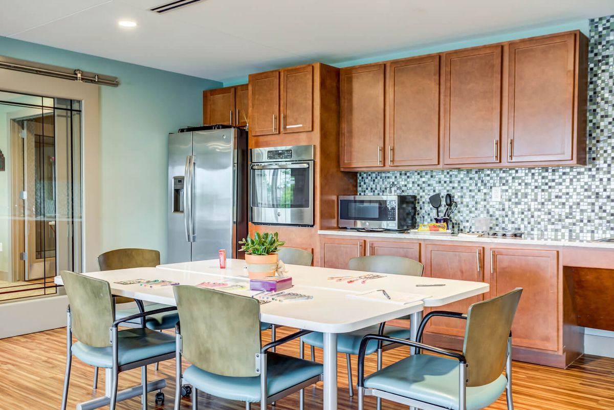 A modern kitchen and dining area with wooden cabinets, a stainless steel refrigerator, and a spacious dining table.