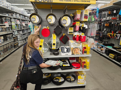 A shopper browsing through a display of cookware in a retail store.