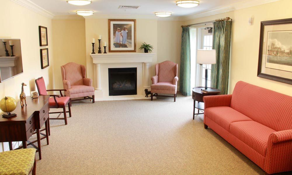 A cozy living room with armchairs, a sofa, and a fireplace.