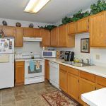A cozy kitchen with wooden cabinets, featuring a fridge, oven, microwave, and dishwasher.