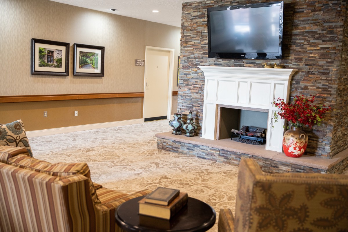 A cozy living room with a stone fireplace and mounted TV, featuring comfortable seating and tasteful decor.