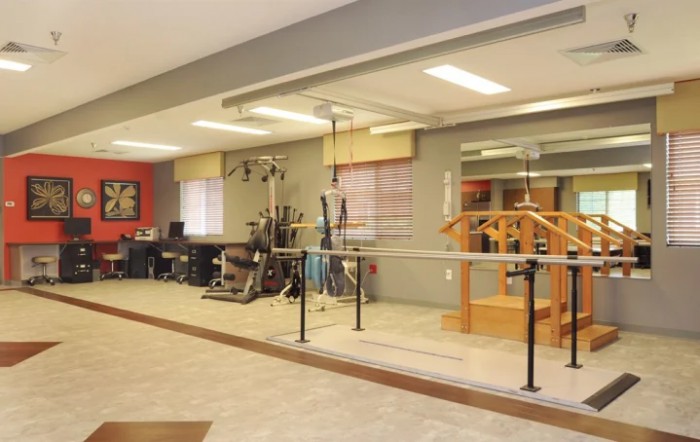 A well-equipped fitness and rehabilitation center with various exercise machines and mirrors reflecting the interior.