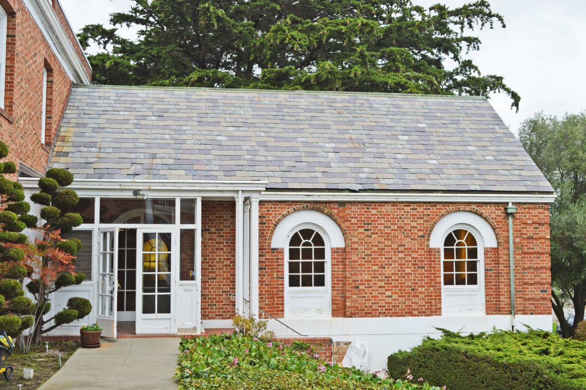 A brick house with arched windows and a glass entryway.