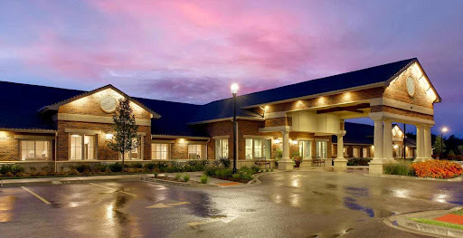 A modern hotel at dusk, reflecting vibrant colors in the sky after rain.