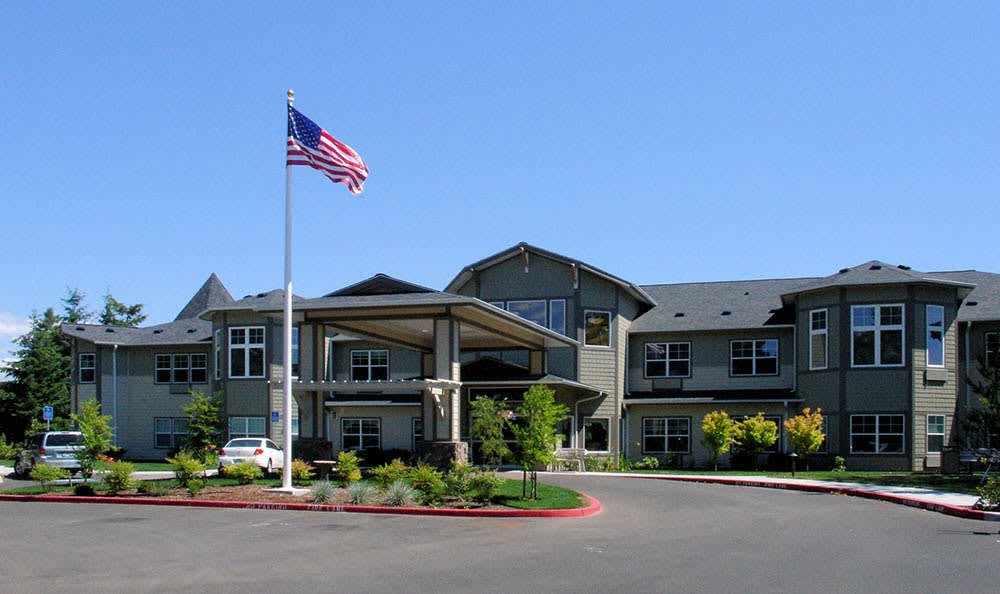 A modern building with a US flag flying in front under a clear blue sky.