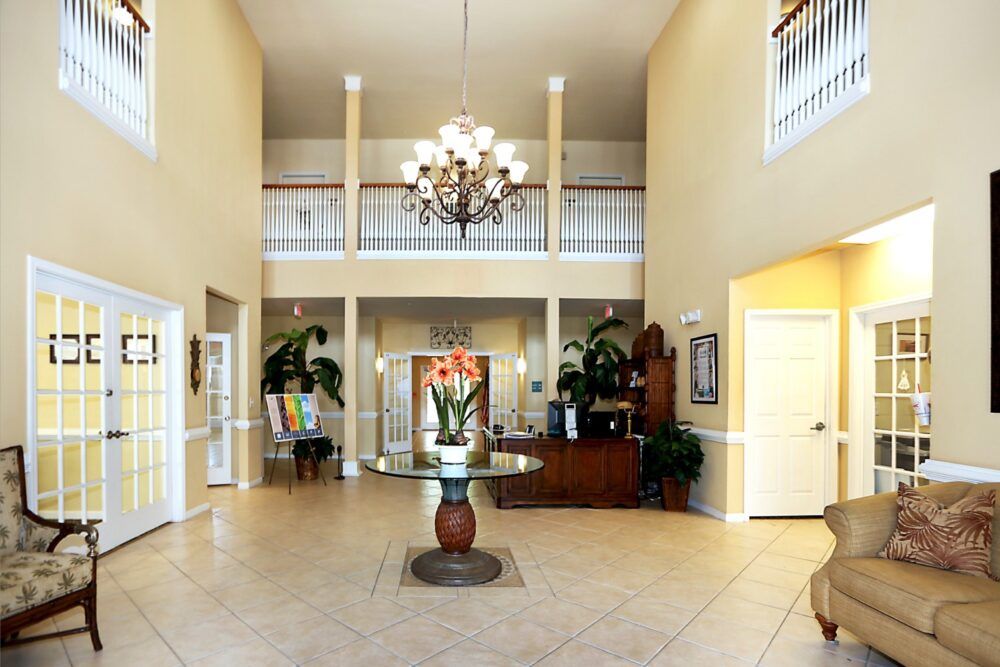 A spacious lobby with elegant decor featuring a chandelier and reception desk.