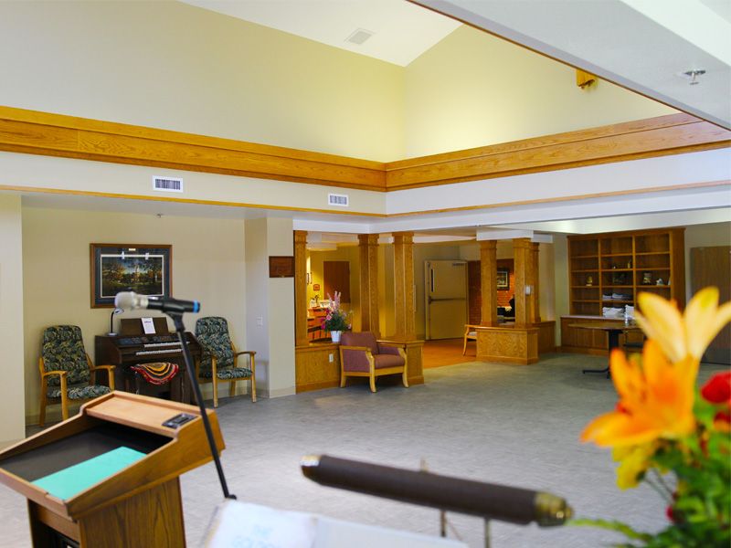 A brightly lit lobby with a reception desk and seating area, featuring wood accents and a carpeted floor.