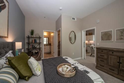 A modern bedroom with stylish decor, featuring a neatly made bed, decorative pillows, and accent furniture.