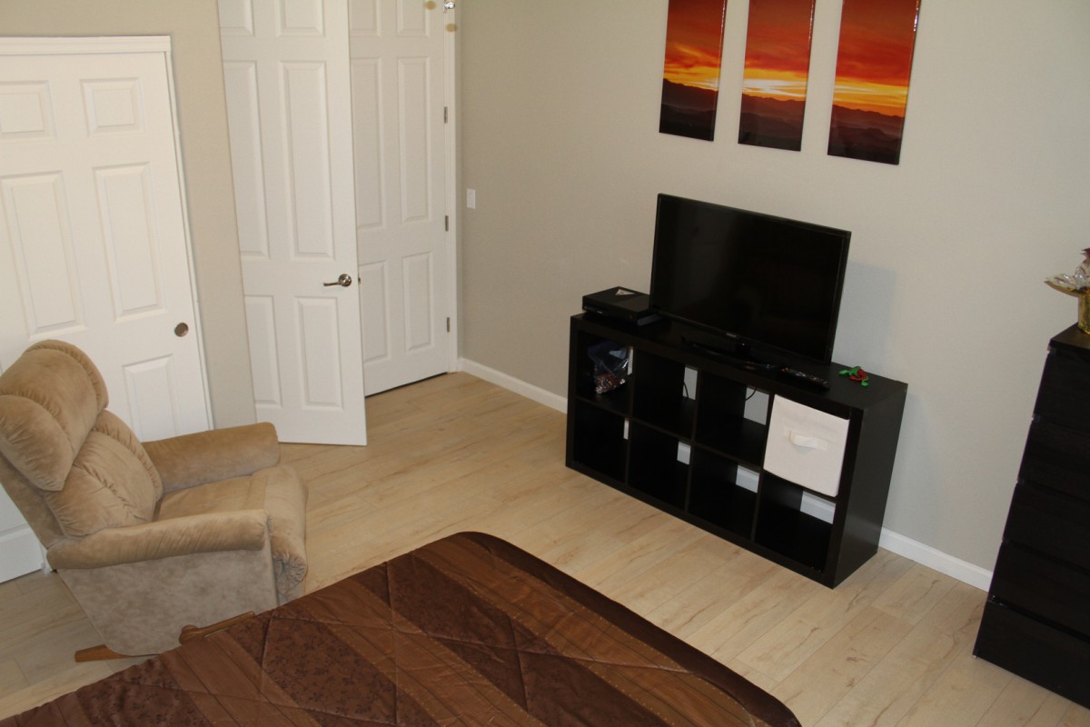 A cozy bedroom featuring a television on a stand, with decorative paintings on the wall.