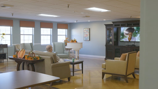 A cozy living room setting in a senior living facility, complete with comfortable seating and a television.