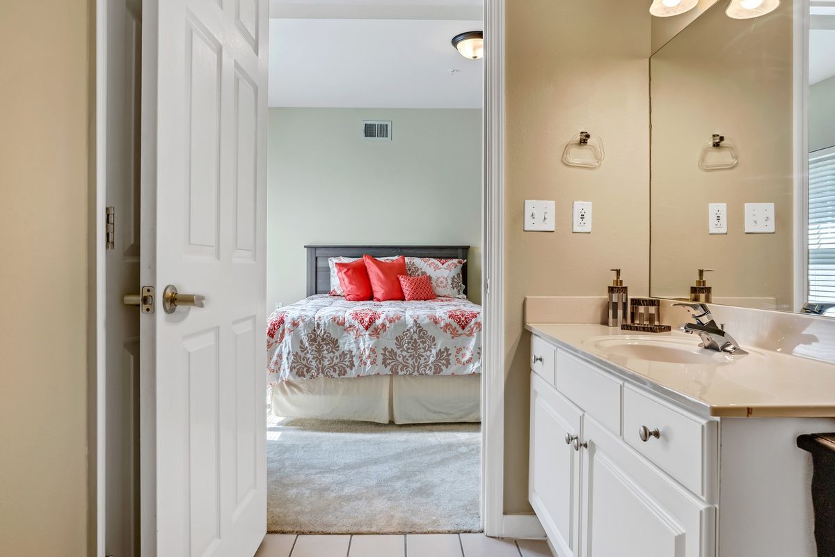 A view from the bathroom into a cozy bedroom with a neatly made bed and decorative pillows.