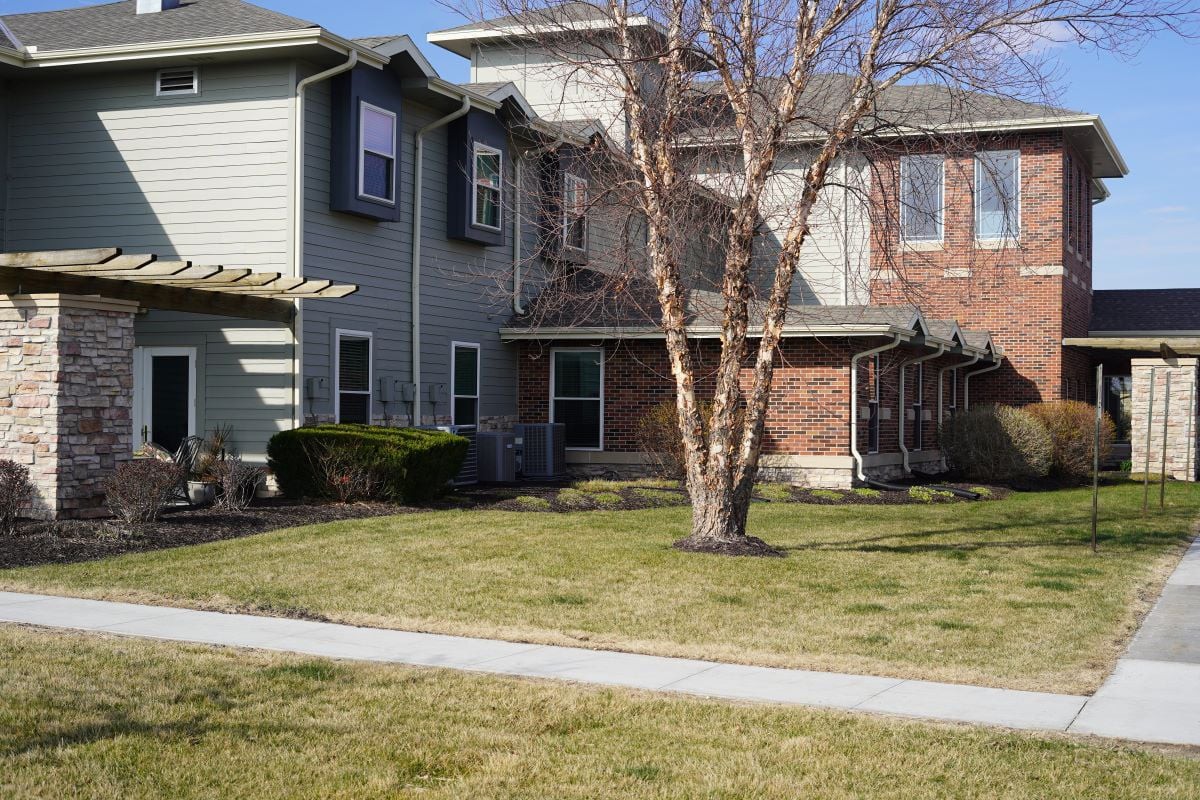 A suburban residential house with a tree and well-kept lawn.