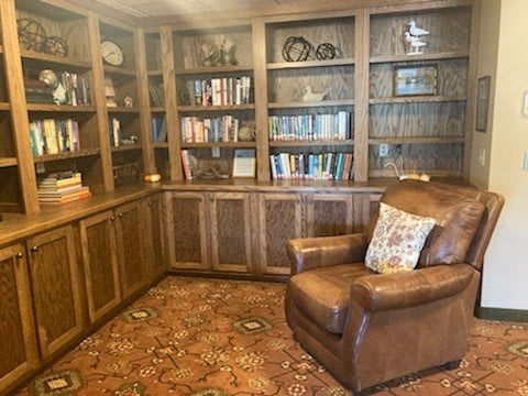 A cozy home library with wooden bookshelves, a leather armchair, and decorative items.