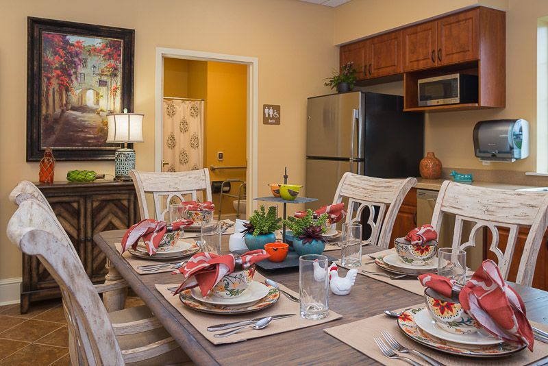 A cozy dining room with a beautifully set table and kitchen in the background.