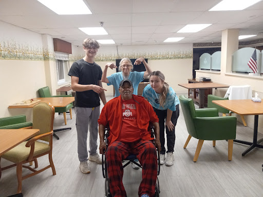A group of caregivers and a resident enjoy a light-hearted moment in the care facility.