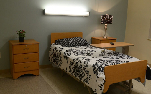 A cozy bedroom featuring a neatly made bed with floral bedding and modern furniture.