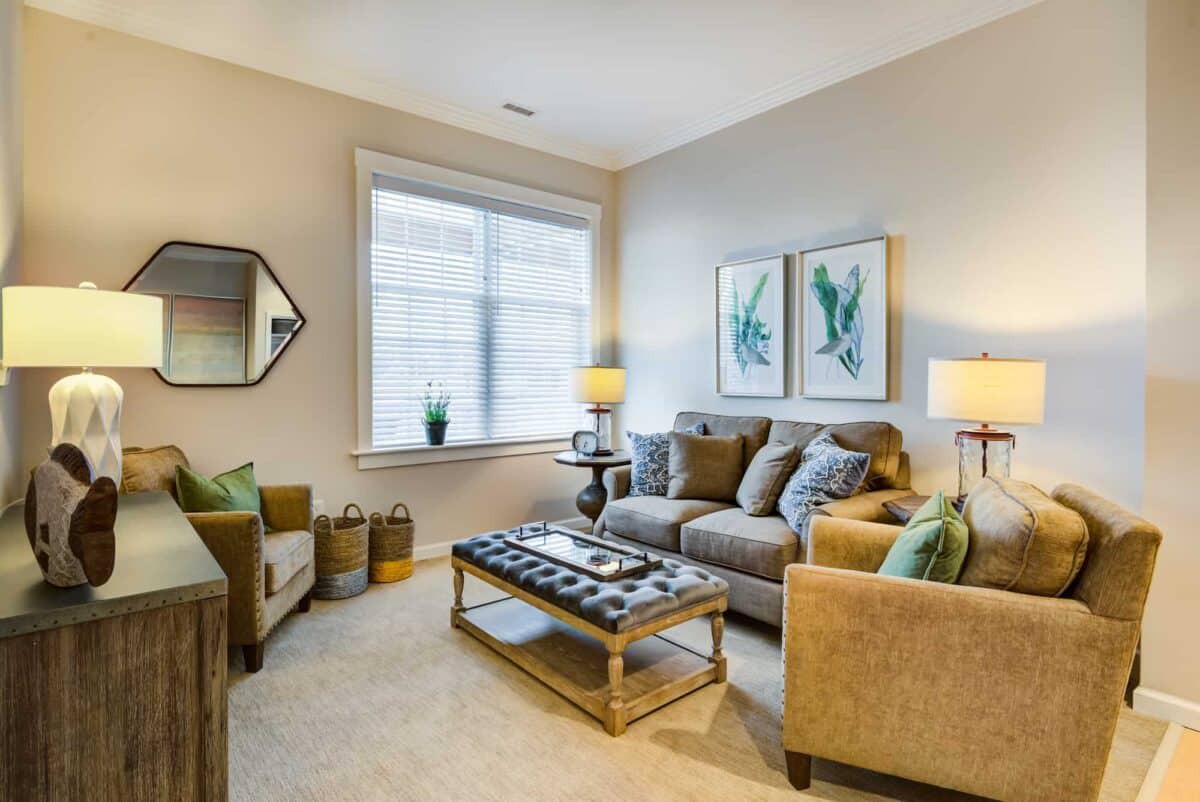A cozy living room featuring a comfortable sofa and armchair, accented with decorative pillows and artwork on the walls.