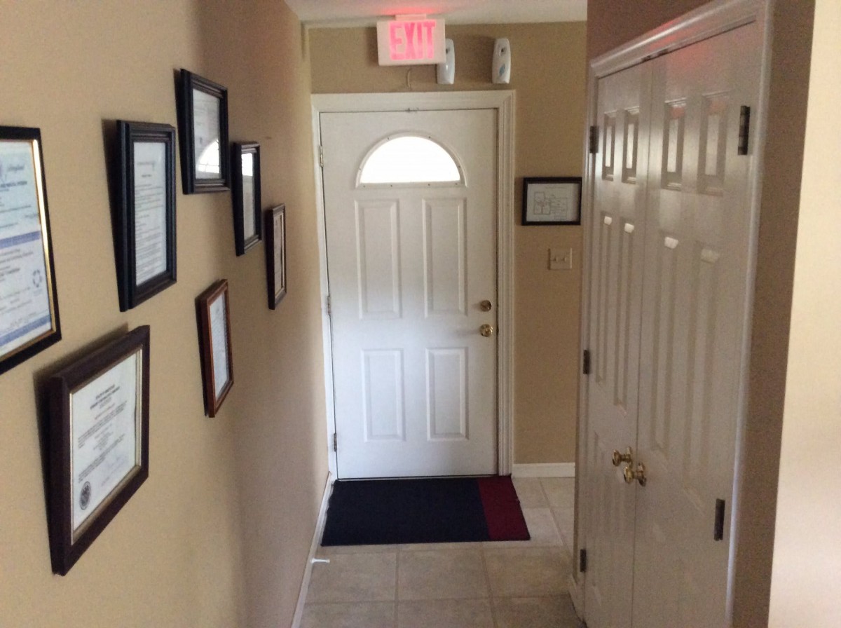 A hallway with framed pictures on the wall leading to a closed door.
