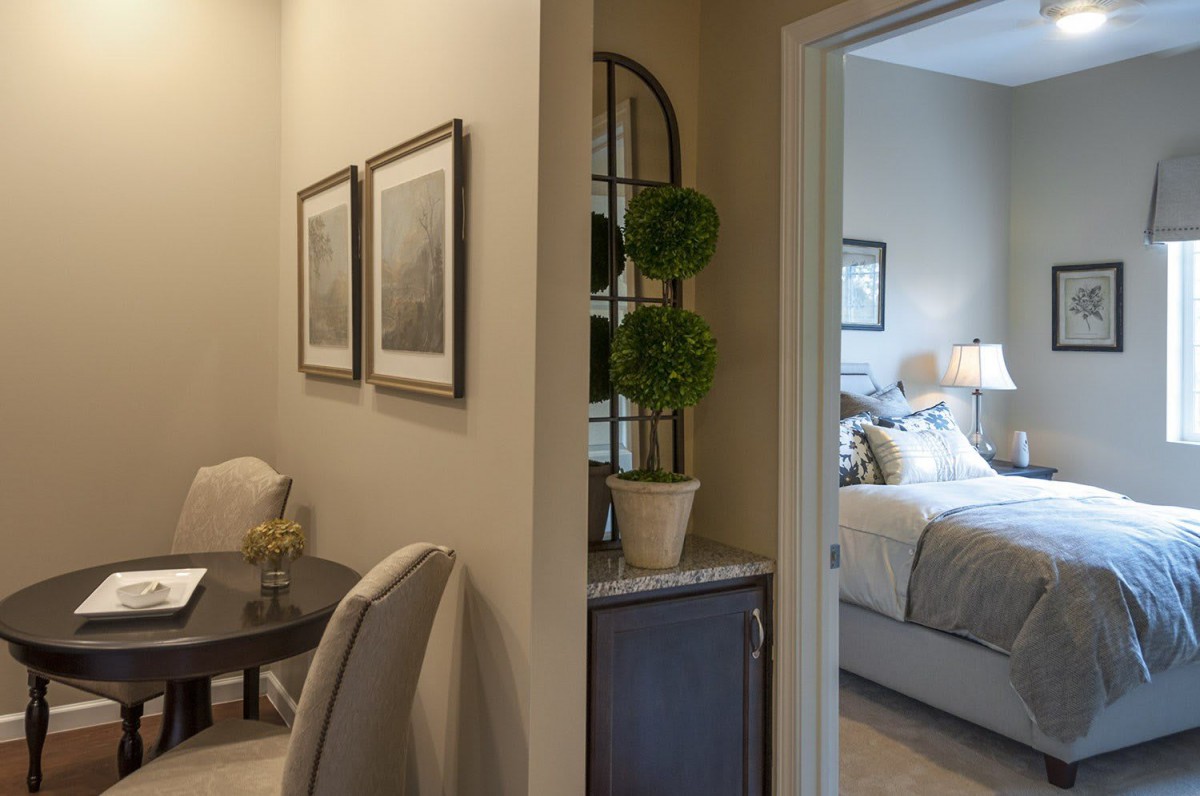 A cozy interior view showing a transition from a living area to a bedroom, featuring elegant furniture and decor.