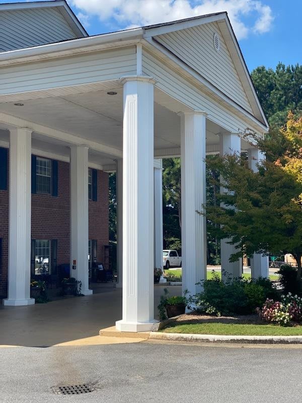A building entrance with tall columns and surrounding trees.