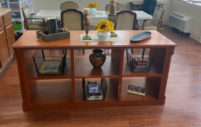A neatly organized bookshelf with decorative items and reading materials in a dining area.