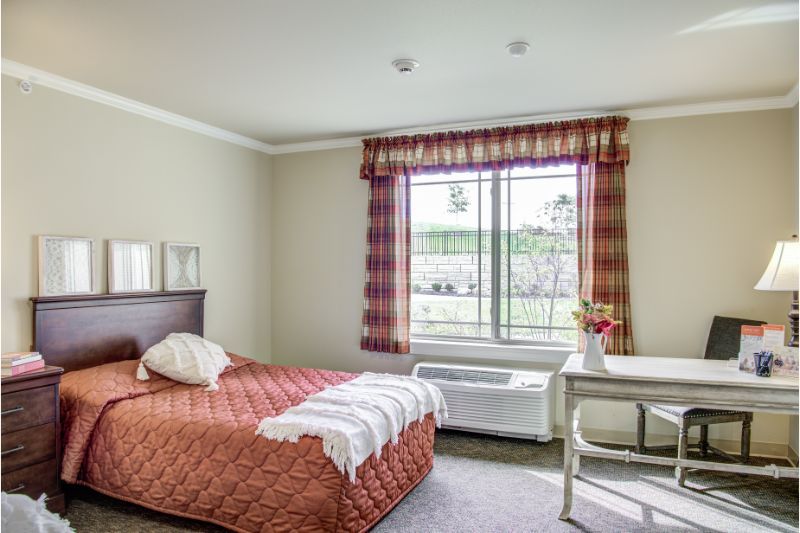 A cozy bedroom with a single bed, plaid curtains, and a small desk by the window.