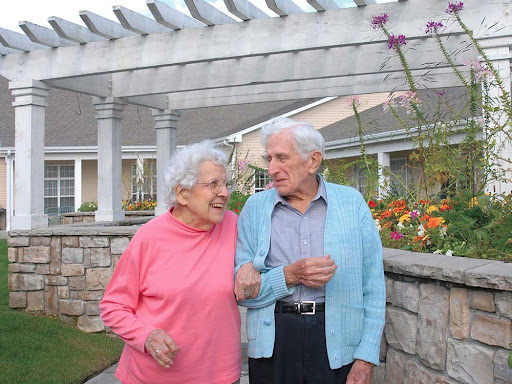 A joyful moment shared between an elderly couple enjoying a stroll in the garden.