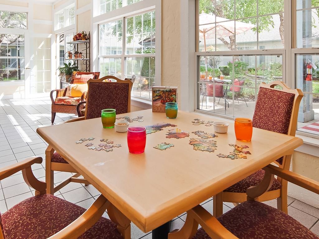 A bright living room with a table set for casual gathering, featuring colorful cups and comfortable seating.