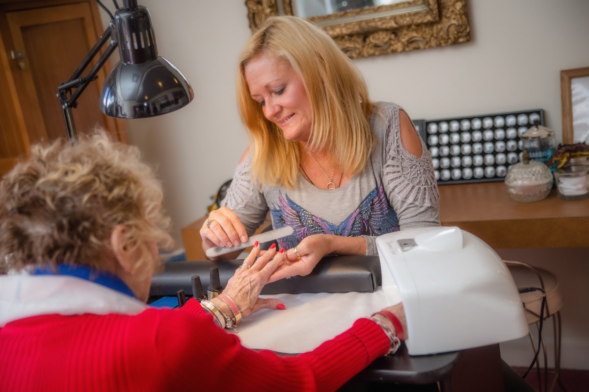 A woman provides a manicure service to a client at a nail salon.
