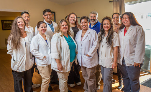A cheerful team of healthcare professionals posing together in a warm setting.