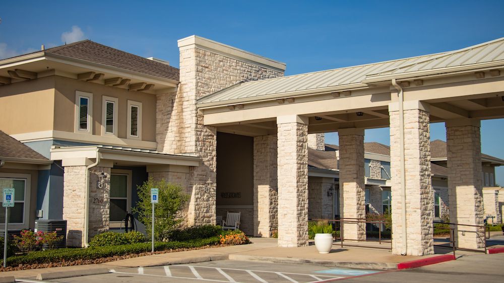 A modern building with a stone exterior and covered entrance, captured in daylight.