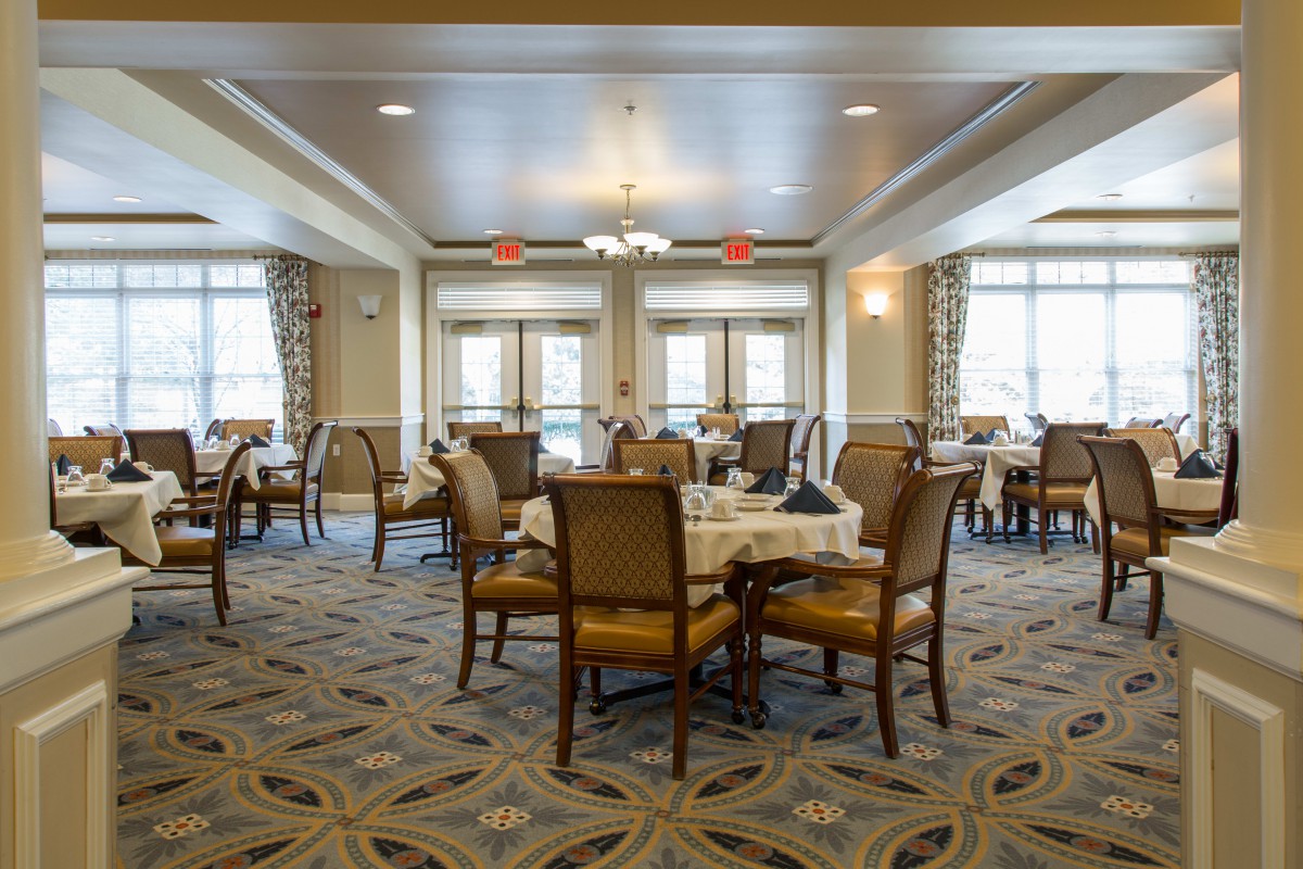 A well-lit dining room with neatly arranged tables and chairs.