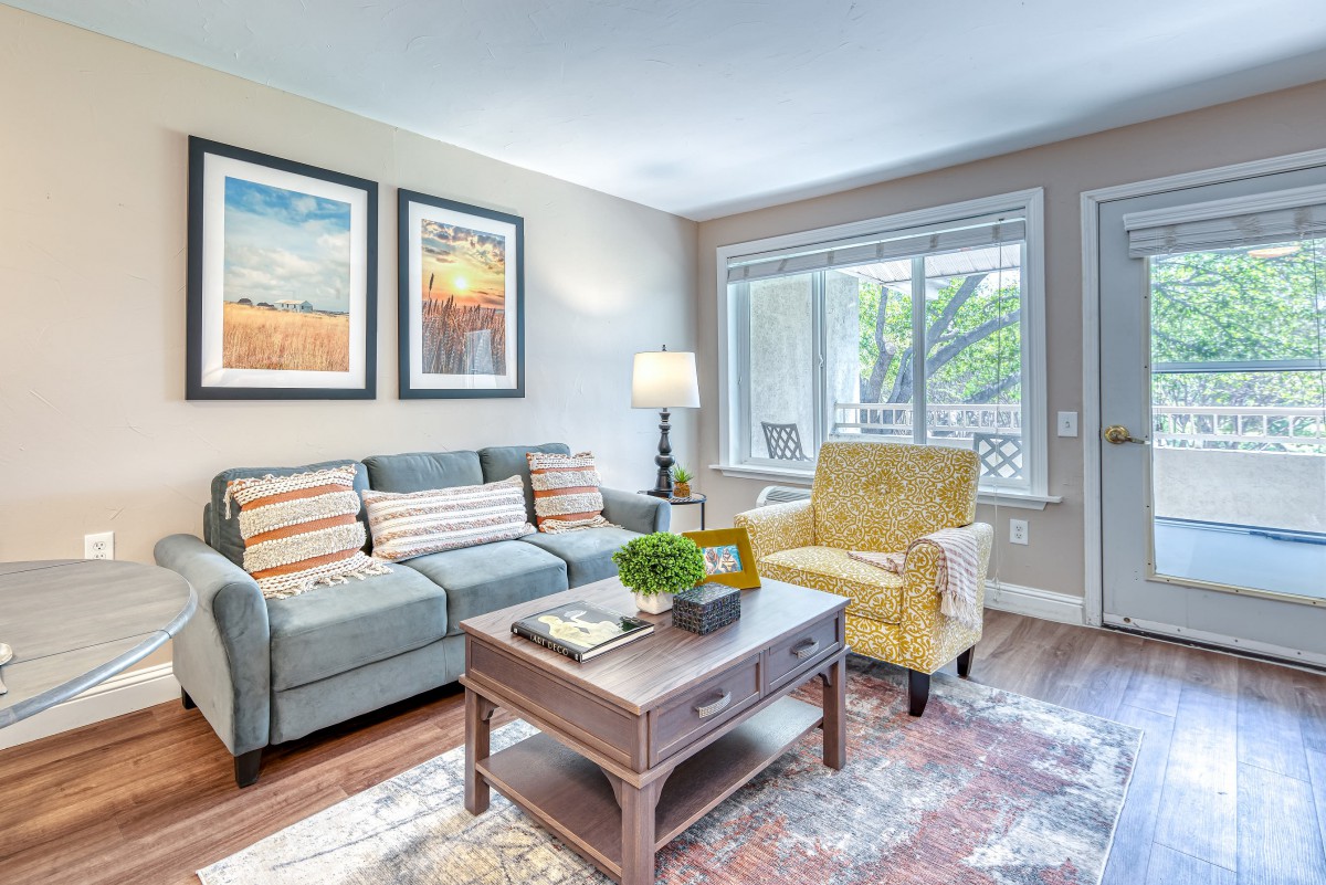 A cozy living room with a sofa, armchair, coffee table, and large window.