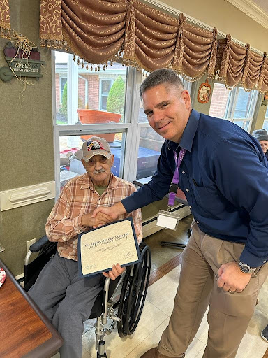 A heartwarming moment as a senior citizen receives an award during a community celebration.