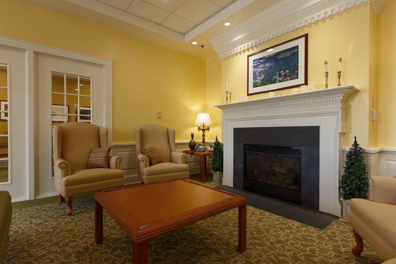 A cozy living room with a fireplace, armchairs, and a wooden coffee table.