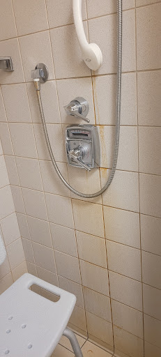 A close-up view of a shower setup, highlighting water stains on the tiles and the shower controls.