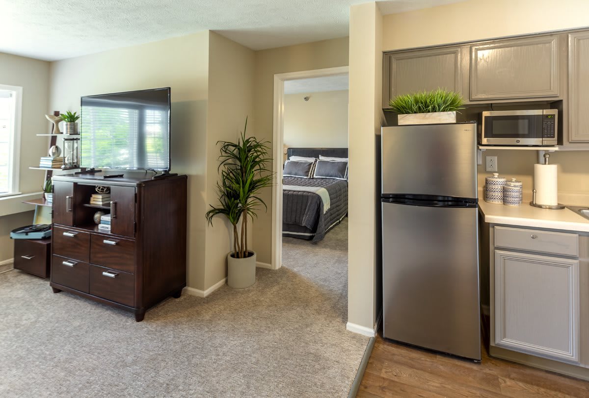 A modern apartment interior featuring a cozy living room, a compact kitchen, and a glimpse into the bedroom.