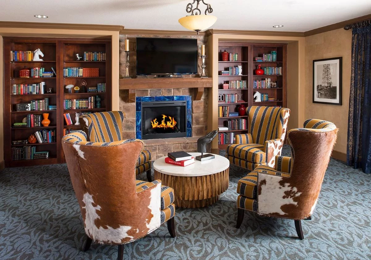 A cozy living room with a fireplace surrounded by bookshelves and comfortable seating.