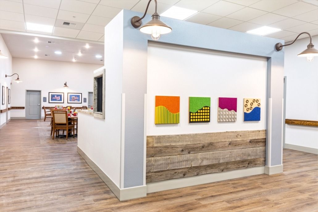 A modern art gallery interior featuring vibrant paintings and wood flooring.